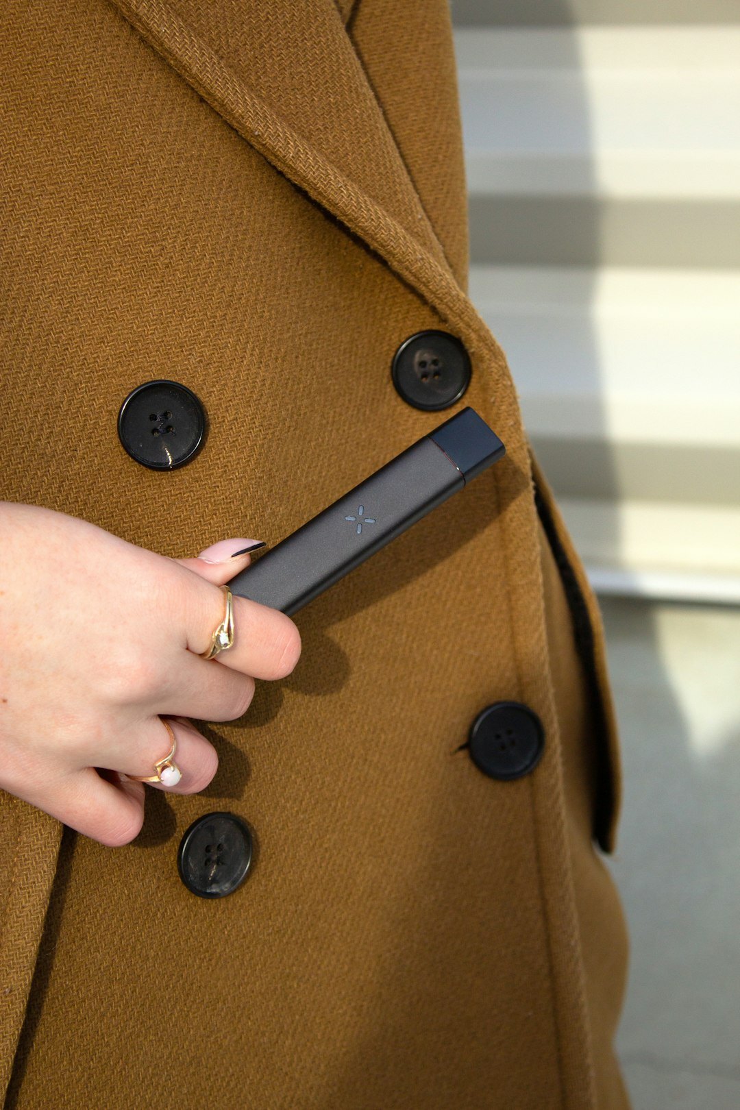 Fashion editorial close-up of tailored coat with brass button detail