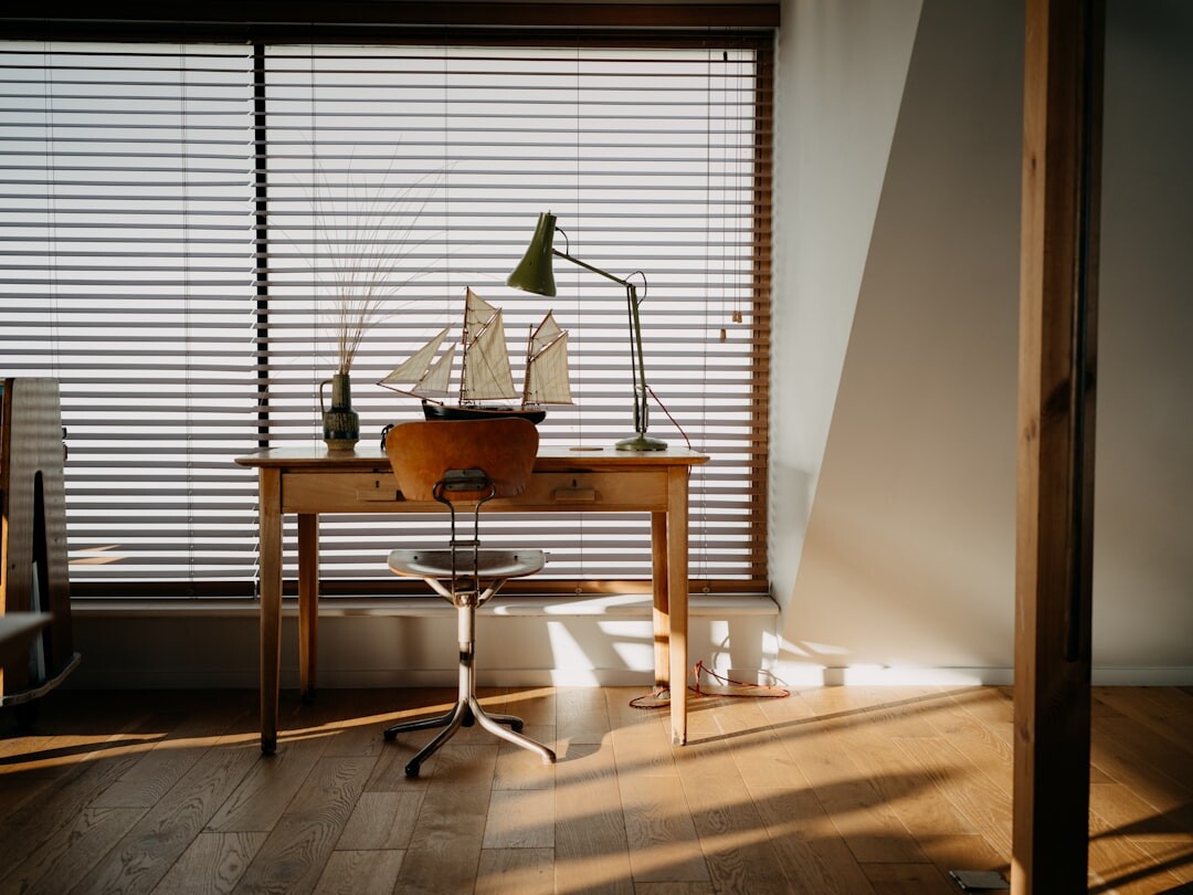 Telephone and notebook on a wooden desk near a window