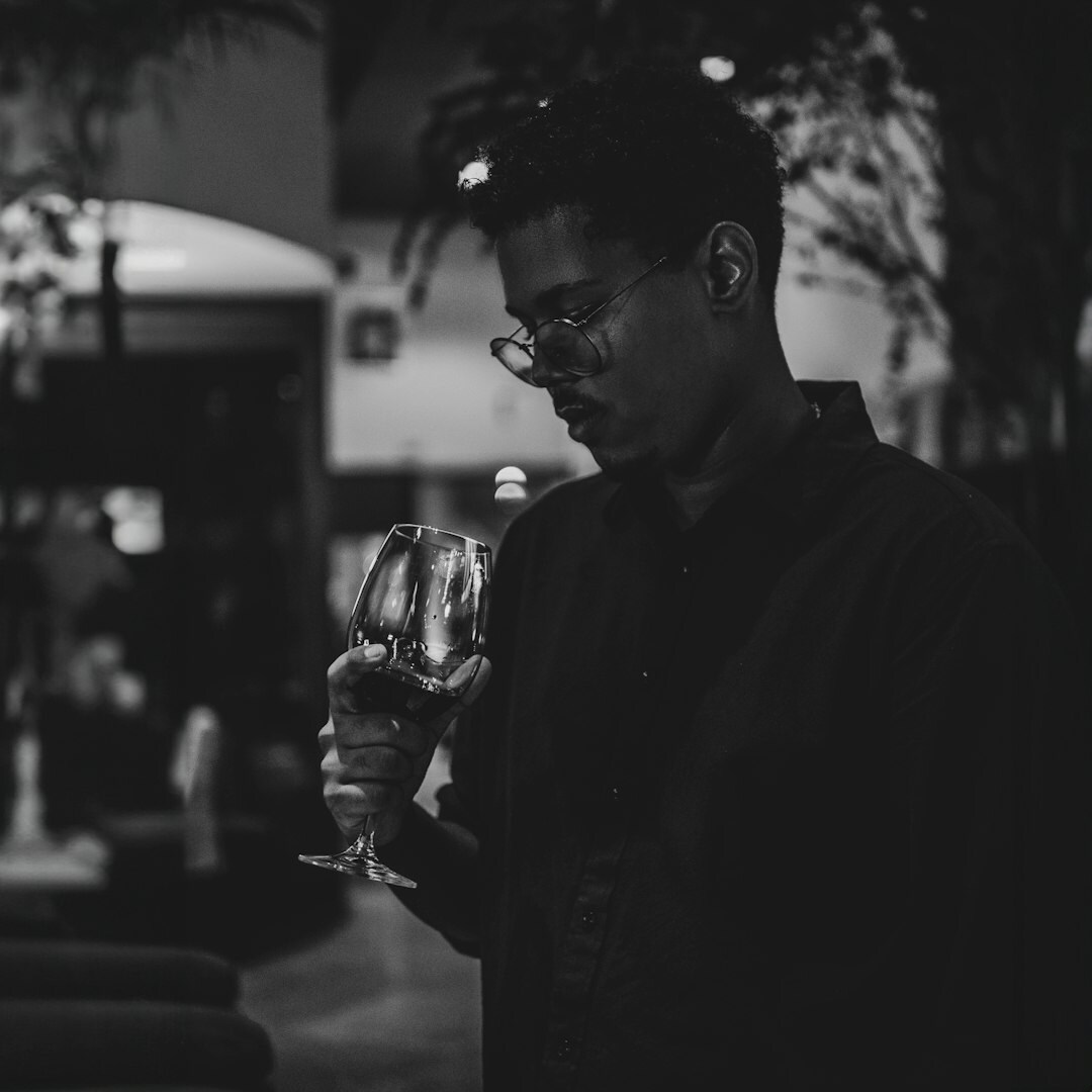 Close-up of a hand holding a glass of red wine at an evening event